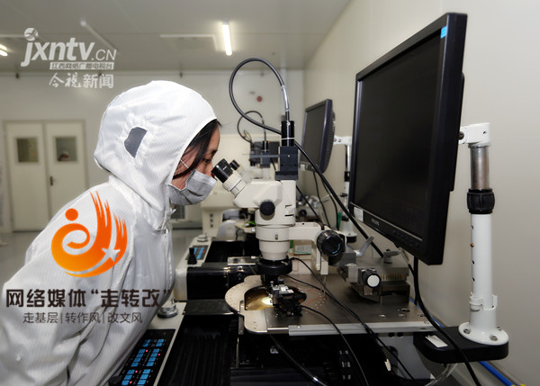 中心工作人员正在对芯片进行测试，测试过程中通过显微镜观察芯片的质量。