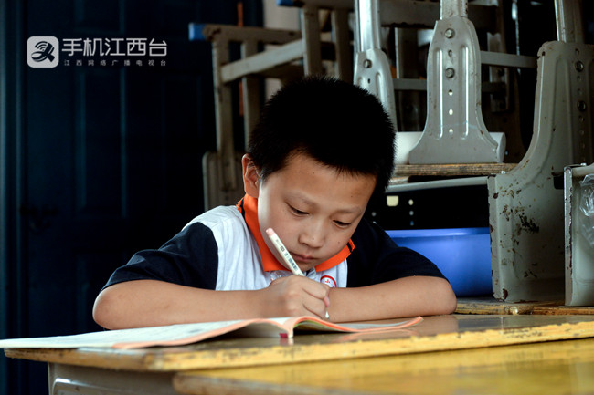 桂湖小学五年级学生黄雨泽在安置教室里写作业。记者刘起福 摄