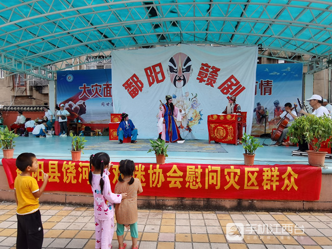 鄱阳县赣剧饶河戏戏迷协会送戏进五一中心学校安置点，小朋友也来看戏。记者陶望平 摄